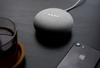 google home mini on a table with iPhone 7
