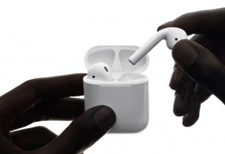 Wirelessly charged Apple AirPods in hands of a person