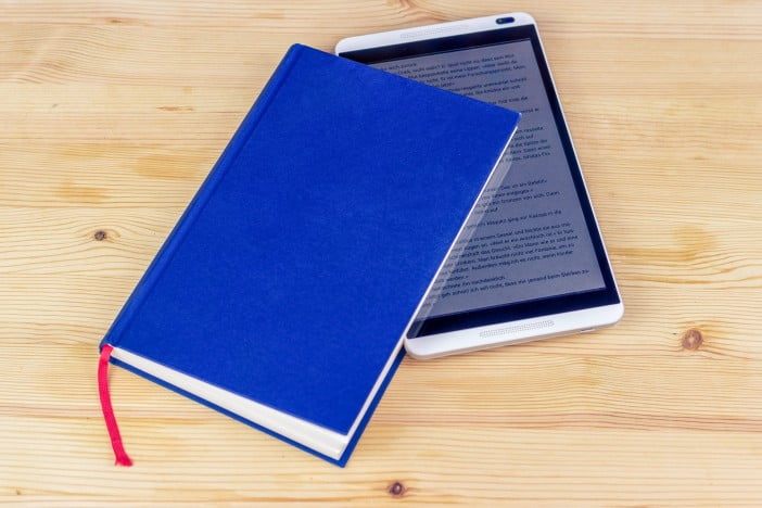 A Photo Of The Tablet With An Ebook Opened, Placed Inside A Blue Book