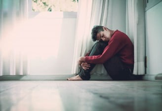 Photo of a depressed boy sitting down on the floor