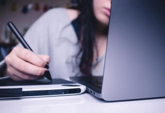 a woman designing using a wacom digital touchpad and a pencil