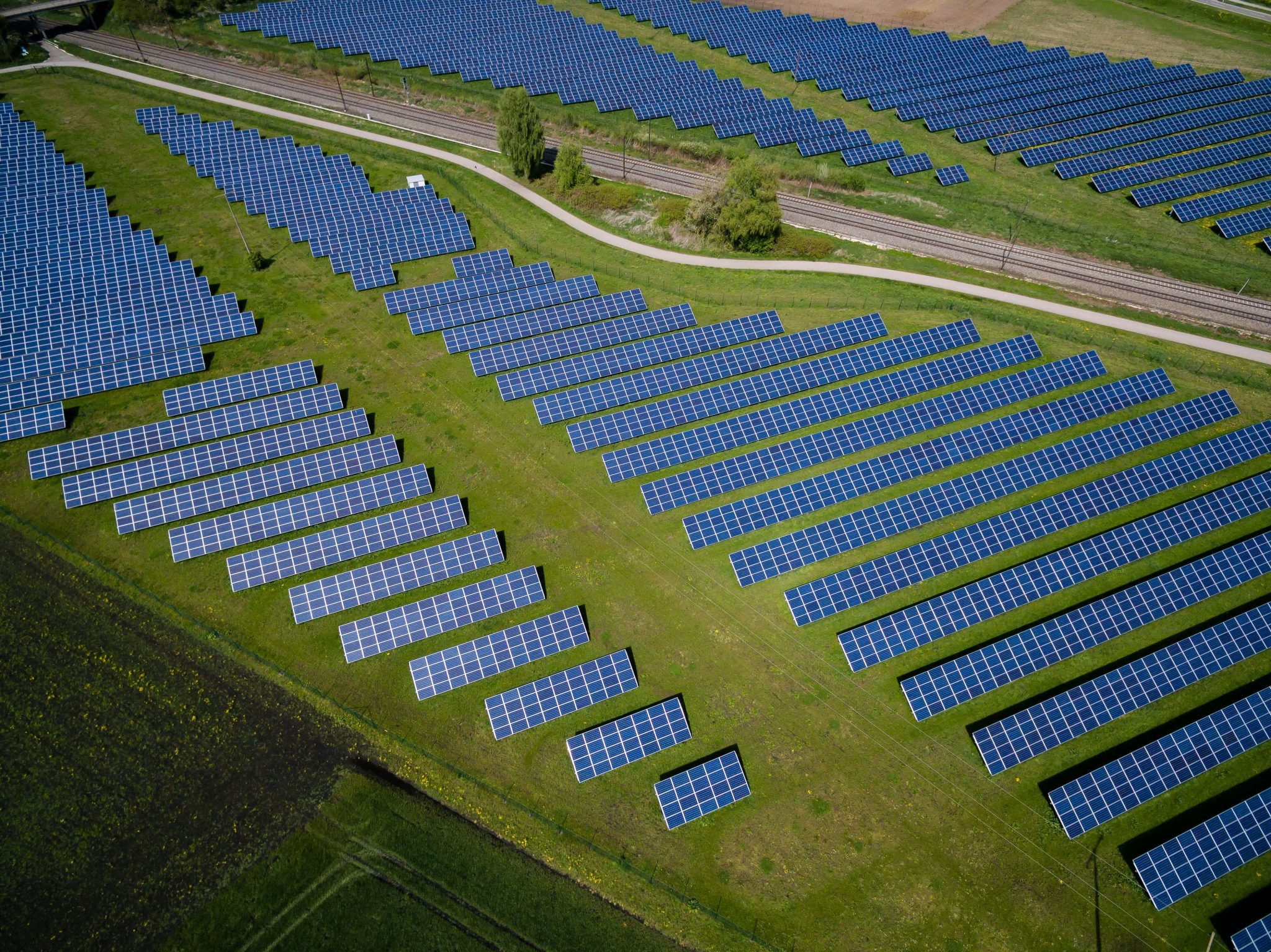 An aerial photo of solar panels on green grass
