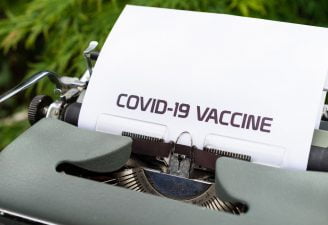 An image of type writer writing COVID-19 Vaccine